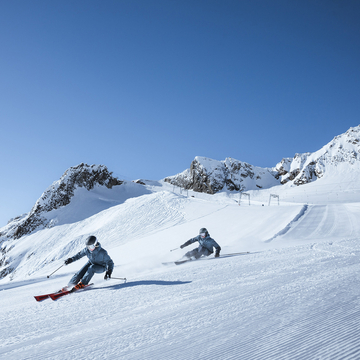 Skifahrerin und Skifahrer im Frühling auf Piste am Stubaier Gletscher