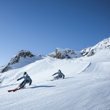 Skifahrerin und Skifahrer im Frühling auf Piste am Stubaier Gletscher